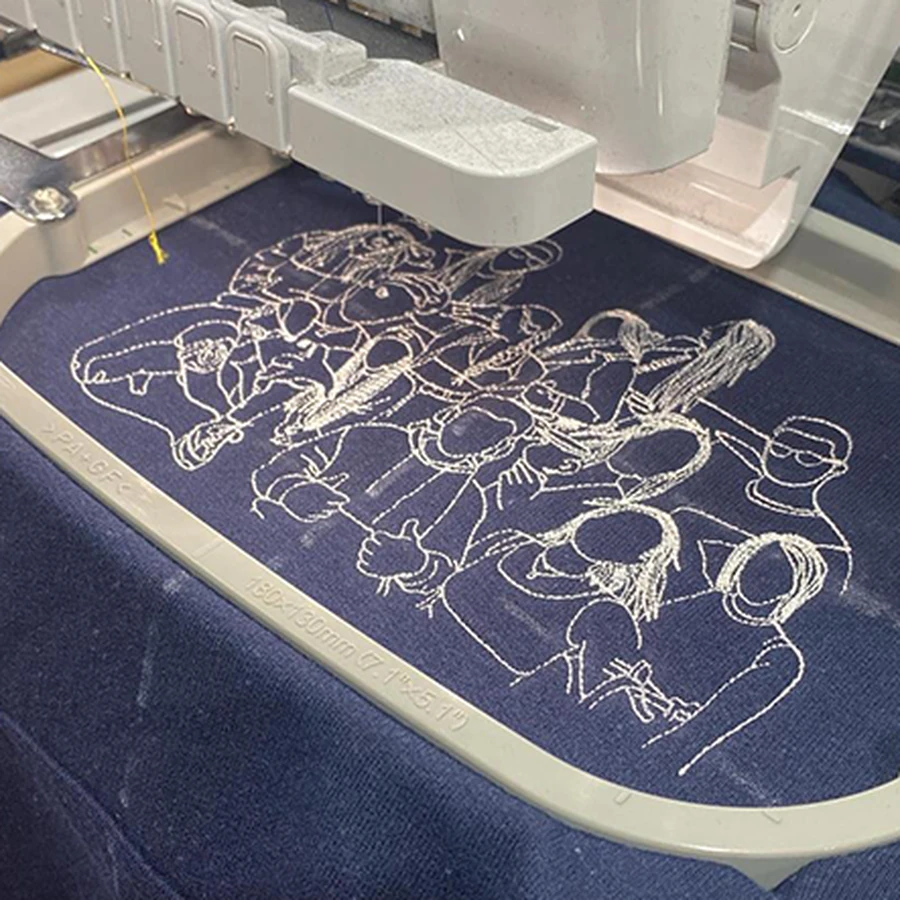 Máquina realizando un bordado detallado sobre tejido azul